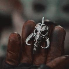 a person's hand holding a silver ring with a horse skull on the middle