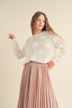 a woman in a white sweater and pink pleated skirt