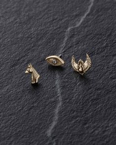 three gold - plated metal pins with an eagle, bird and eye on them