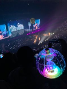 a person holding up a colorful object in front of an audience at a music concert