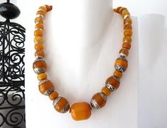 Short necklace made of orange resin beads, also known as "faux ambar" or "african amber". In the 20's and 30's they were very popular, in many countries they were used as a substitute for amber in necklaces. Some of the beads in the chain are adorned with engraved silver foil. Wavy silver beads complement the necklace. The chain closes with a sterling silver S hook. **Used material** tibetan resin beads, african amber, silver beads, sterling silver clasp, jewelry wire **Size/Dimensions/Weight** Traditional Orange Gemstone Bead Necklaces, Bohemian Orange Necklaces With Silver Beads, Antique Amber Necklaces With Polished Beads, Antique Handmade Amber Beaded Necklaces, Traditional Orange Gemstone Beads Necklace, Traditional Yellow Gemstone Beads Necklace, Handmade Antique Amber Beaded Necklace, Antique Amber Necklace With Polished Beads, Antique Handmade Amber Beaded Necklace