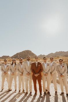 a group of men standing next to each other in front of a desert landscape with mountains