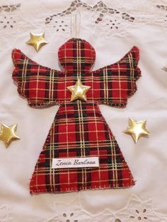 a red and black plaid angel ornament on a white doily with gold stars