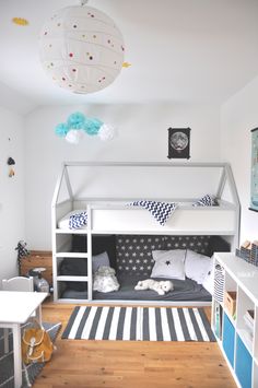 a room with a bunk bed, desk and shelves on the wall next to it