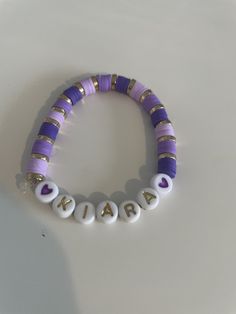 a purple and white beaded bracelet with gold letters