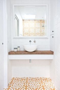 a white sink sitting under a bathroom mirror next to a counter top with a bowl on it