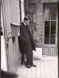 an old photo of a man standing in front of a door with his hand on the side