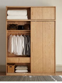 an open wooden wardrobe with clothes hanging on it