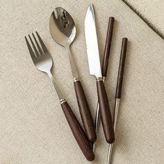 four knives, forks and spoons sitting on top of a beige cloth covered table