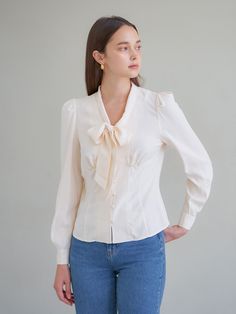 Editor's NotesV-neck blouse with a tied bow and long sleeves. Front opening with fabric button closure.- V-neck- Long sleeve- Bow tie- Button closureMeasurements(in.)Size: One Size (XS-M)- Total Length: 21- Shoulder: 13.3- Chest: 17.3- Waist: 15.5- Armhole: 8.6- Sleeve length: 24.4- Collar height: 2.2*All sizes are based on cross-section.*Errors may occur depending on the measurement method.*The model's arms and legs are long, so the sleeves or the length may appear short. Please refer to the size chart.*Model Info (ELLE): Height 5'9 / Bust 31 / Waist 25 / Hip 35Composition & Care- 62% Modal, 38% Rayon- Dry clean onlyDesigner- by VEM.VER Spring Button-up Blouse With Tie Sleeves, Tie Neck Blouse With Button Closure For Work, Feminine Bow Tops For Workwear, Feminine Tops With Bow For Workwear, Feminine Tie Neck Blouse With Bow, Feminine Tops With Bow And Tie Neck, Feminine Bow Tops For Work, Fall Tie Neck Blouse With Bow, Feminine Fall Blouse With Bow