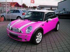 a bright pink car with white stripes parked in a parking lot