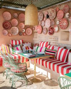 a table with red and white plates on the wall behind it, along with green wicker chairs