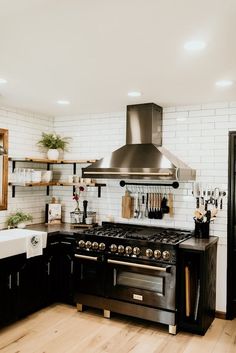 a kitchen with black cabinets and stainless steel stove top oven in the center, surrounded by wooden flooring