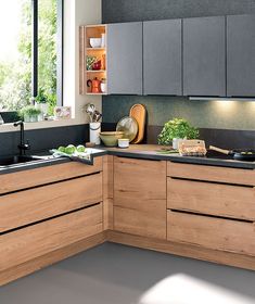 a modern kitchen with black counter tops and wooden cabinetry, along with potted plants