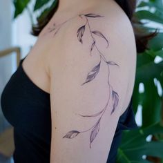 a woman with a tattoo on her shoulder has leaves in the shape of an arrow