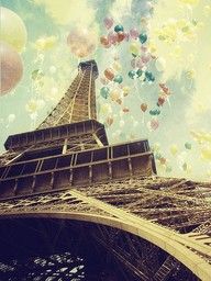 the eiffel tower has many balloons floating in the sky above it and below it