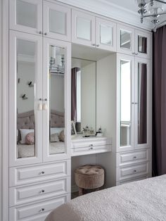 a white bedroom with mirrored closets and dressing table in the corner by the window