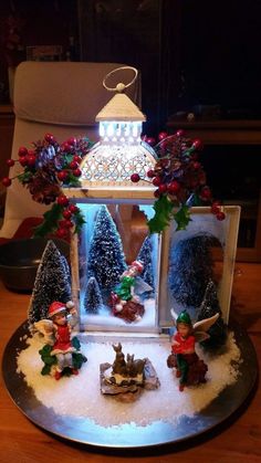 a christmas scene made out of snow and fake trees in a glass case on a table