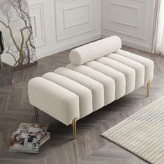 a white couch sitting on top of a hard wood floor next to a magazine rack