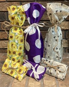 three wrapped gift bags sitting next to each other on top of a stone floor with sunflowers