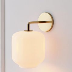 a wall light that is on the side of a wall with a white glass shade