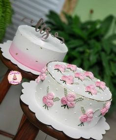 two tiered wedding cakes with pink roses on them sitting on wooden stands next to each other