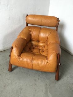 a brown leather chair sitting on top of a cement floor next to a white wall