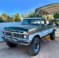 an old pick up truck is parked under a carport