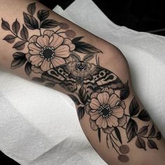 a black and white photo of a moth on a flowered arm with flowers in the background