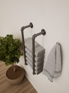 there is a potted plant and towel rack on the wall next to towels that have been folded