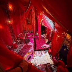 a bed covered in pink and red fabric with lights on it's headboard