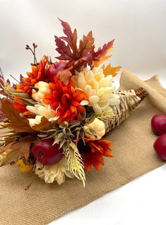 a bouquet of flowers sitting on top of a burlap bag next to apples