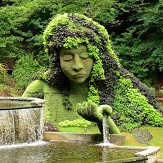 there is a statue that looks like a girl with long hair holding a watering can