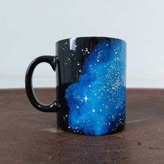 a black and blue coffee mug sitting on top of a wooden table