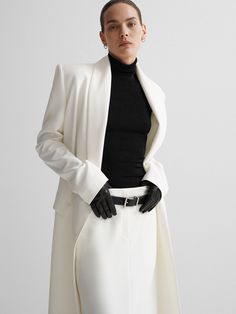 Elegance and Versatility in One Ensemble: Introducing the Women's White Long Blazer Fit-Flare Skirt Set, a stunning ensemble that embodies elegance, versatility, and timeless charm. This two-piece outfit is a harmonious blend of sophistication and modern style, making it the perfect choice for a bride, bridesmaid, wedding guest, or any special occasion where you aim to dazzle. The long blazer features a graceful fit-and-flare silhouette that flatters your figure and exudes a sense of grace. Its shawl lapel adds a touch of classic refinement, making it equally suitable for formal dinners, prom nights, or elegant evening events.  Customized to Perfection: What sets this ensemble apart is its tailored fit, designed to ensure that every aspect of the outfit is personalized to your exact measur Luxury White Turtleneck For Workwear, Luxury Elegant Workwear Blazer, Luxury Elegant Blazer For Workwear, Luxury White Classic Pantsuit, Luxury Formal Blazer With Belt, Modern Luxury Outerwear For Career, Luxury White Outerwear For Office Wear, Luxury Tailored Blazer For Gala, Luxury Classic Long Sleeve Blazer