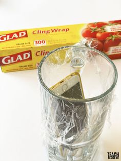 a glass filled with liquid next to a package of glue and tomatoes on the table