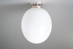 a white light hanging from the ceiling on a gray wall with no one in it