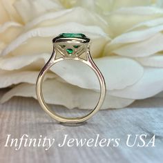 "The ring pictured is lab created emerald #5950 -Approximate total carat weight: 2.70ctw diamond equivalent -Center Stone Size: 9mm - approx. 2.70ct diamond equivalent -Center Stone Shape: round (set with cushion shape bezel) -Gem Type: lab created emerald -Stone Clarity: VS2 -Stone Color: lively green -Moh's Scale: 8.5 hardness -Metal Type and Purity: 14k yellow gold -Setting: bezel set -Stock Ring Size: 5.75 -Country of Manufacturing: USA (Michigan) For customization please contact us. If you Gia Certified Green Sapphire Ring For Formal Occasions, Formal Gia Certified Green Sapphire Ring, Oval Tsavorite Diamond Ring For Formal Occasions, Elegant Green Sapphire Ring Gia Certified, Oval Tsavorite Ring With Center Stone, Classic Tsavorite Diamond Ring For Anniversary, Fine Jewelry Emerald Ring With Princess Cut, Formal Emerald Solitaire Birthstone Ring, Formal Cluster Ring With Emerald Cut And Halo