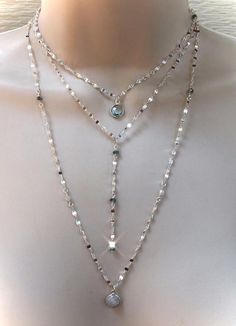 This is one of my favorite chains to use, so fluid and shimmery. This cool tone sterling silver picks up all the colors in the rainbow. I placed faceted moonstones and blue topaz stones intermittently with bezel pendants on two of the strands.Each strand is separate with its own clasp and extension chain. Each necklace is sold separately or you can purchase all three as a set at a lower price.The top necklace with the Blue Topaz bezel pendant measures 15" inches and comes with an additional 2" i Cool Tone Jewelry, Silver Lariat Necklace With Natural Stones, Dainty Silver Necklace With Natural Stones, Silver Adjustable Teardrop Crystal Necklace, Silver Adjustable Teardrop Crystal Necklaces, Silver Wire Wrapped Lariat Necklaces, Silver Gemstone Long Necklace, Adjustable Silver Lariat Necklace With Gemstone, Silver Gemstone Lariat Necklace