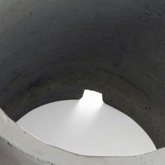 a white object sitting in the middle of a cement structure with light coming through it