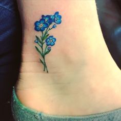 a small blue flower tattoo on the ankle