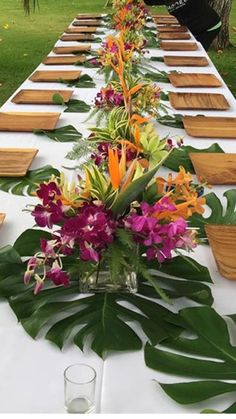 a long table is set up with flowers and place settings for an outdoor dinner party