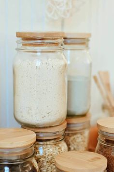 jars filled with different types of food sitting on top of a counter next to wooden spoons