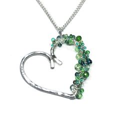 Introducing the Irish at Heart pendant! Made of silver-filled wire, this heart-shaped pendant is decorated on one side with a mix of beads in all different shape, sizes, and shades of green. Perfect for celebrating St. Patrick's Day! From tiny seed beads to faceted rondelle crystals, they are all wrapped onto the heart pendant to create a whimsical, one-of-a-kind pendant. The necklace shown in the pictures is the exact one you will receive. The pendant is approximately 35mm wide. The chain is 22 Heart Pendant Beaded Necklaces For Jewelry Making, Heart-shaped Faceted Beads Necklace For Jewelry Making, Bohemian Heart-shaped Jewelry With Faceted Beads, Green Heart-shaped Beaded Necklaces, Handmade Silver Beaded Necklace With Heart Pendant, Silver Beaded Necklace With Heart Charm, Sterling Silver Beaded Heart Necklaces, Silver Heart-shaped Beaded Necklaces, Silver Beaded Heart Necklace