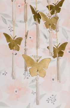 gold butterflies with tassels hanging from chains on a floral wallpapered background