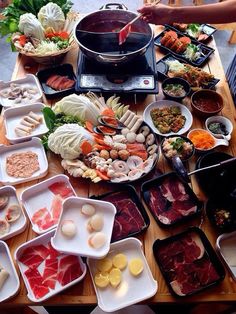 a table topped with lots of food and bowls filled with different types of meats