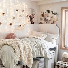 a bedroom with white walls and lights on the headboard, bedding and pillows