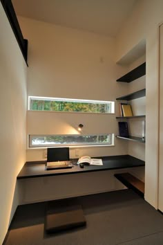 a desk with a computer on top of it in front of a book shelf and window