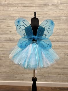 "Fuzzy Duckling Design dresses ~ handcrafted for the little princess in your life. This adorable tutu set includes the tutu skirt, matching ribbon crown and coordinating fairy wings. * The full skirt sparkles and shines with three layers of high quality tulle in matte, shimmer, and glitter finishes. * Tulle is hand-tied onto a wide crocheted band, with an elastic band woven through the material for ease in taking it on and off. * A wide satin ribbon bow is tied to the front of the skirt for an e Blue Themed Costume Dress, Fitted Blue Set For Costume Party, Fitted Blue Sets For Costume Party, Blue Fitted Set For Costume Party, Cute Blue Tutu Dress For Dress-up, Whimsical Blue Dress For Costume Party, Whimsical Blue Dress For Birthday, Whimsical Blue Dresses For Costume Party, Playful Blue Tutu Dress For Dress-up