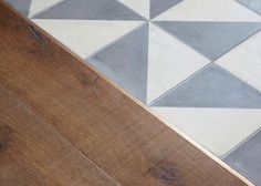 a wooden floor with white and grey tiles on it's sides, next to a wood floor